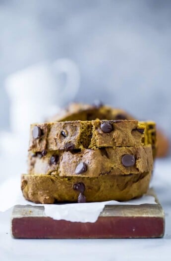 A stack of three slices of chocolate chip pumpkin bread on a piece of parchment paper