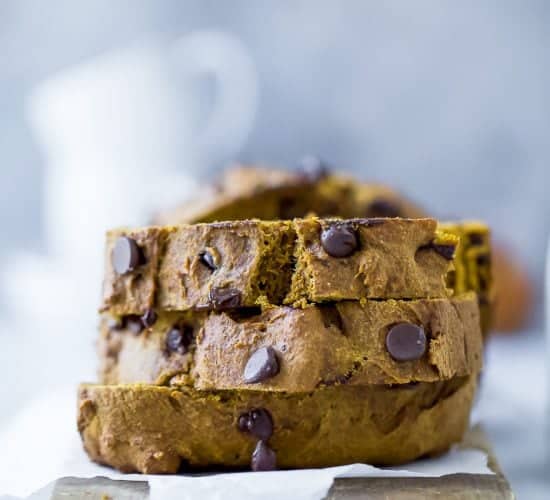 A stack of three slices of chocolate chip pumpkin bread on a piece of parchment paper