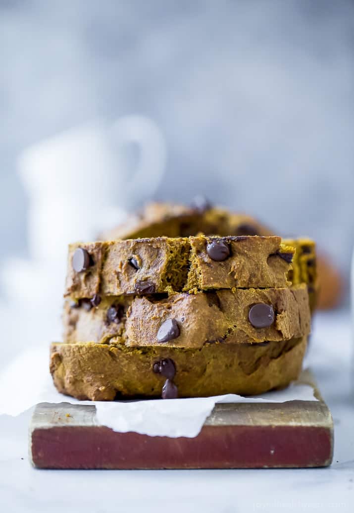 A stack of three slices of chocolate chip pumpkin bread on a piece of parchment paper