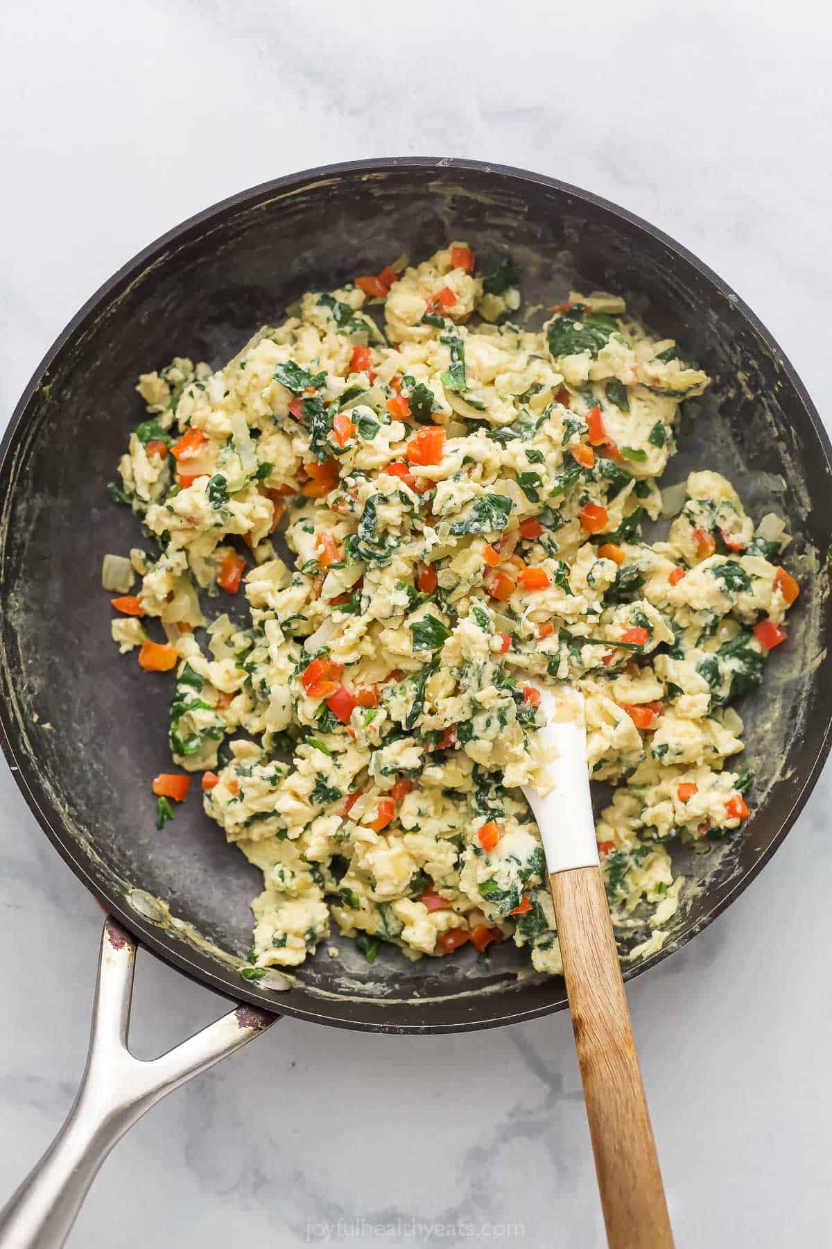Scrambled eggs and veggies in skillet.