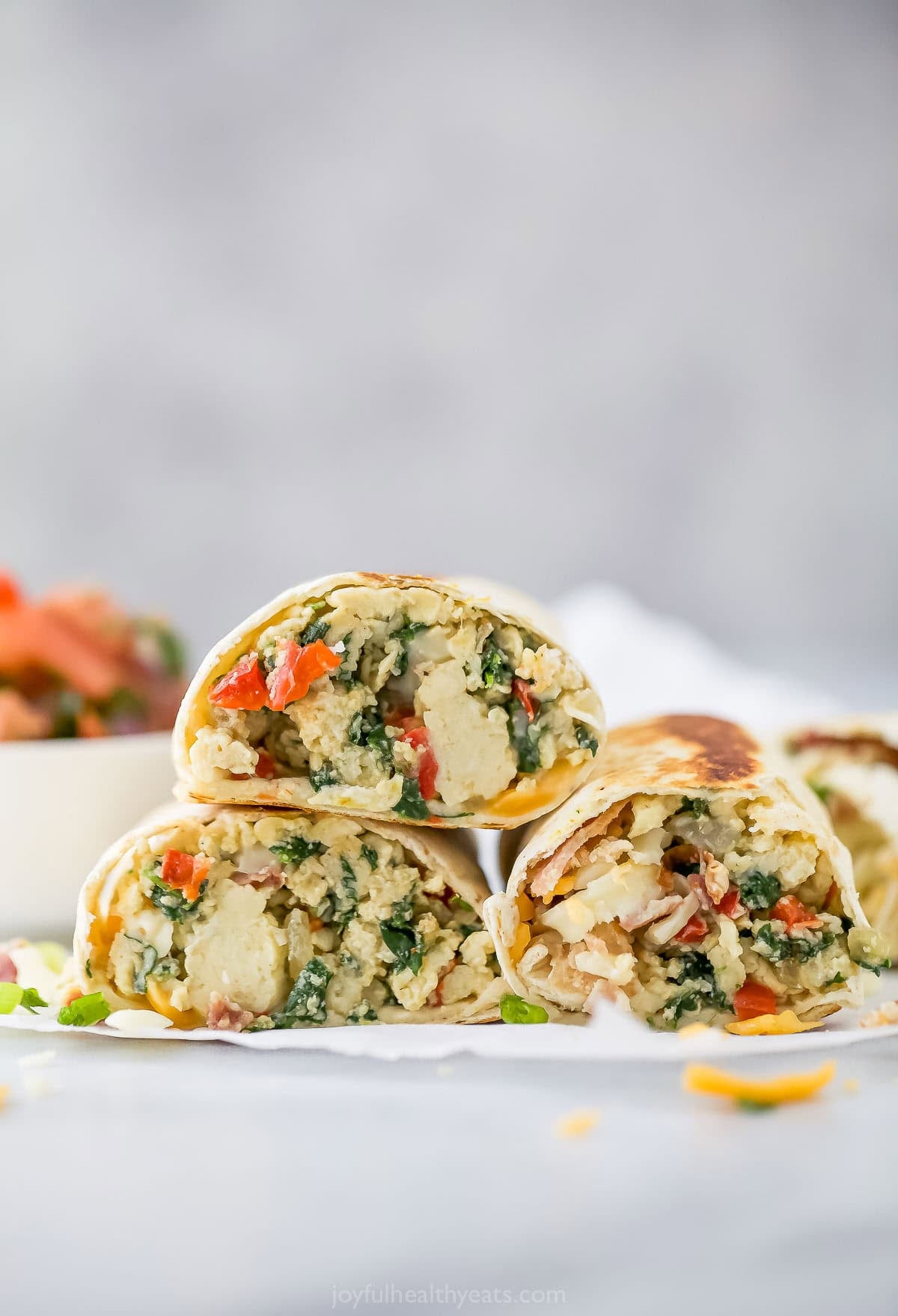 3 stacked freezer breakfast burritos with eggs and veggies.