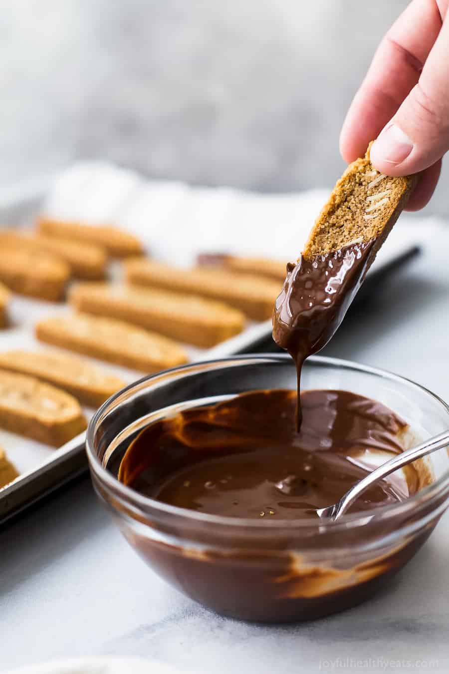 process shot of GLUTEN FREE AMARETTO BISCOTTI being dipped in chocolate