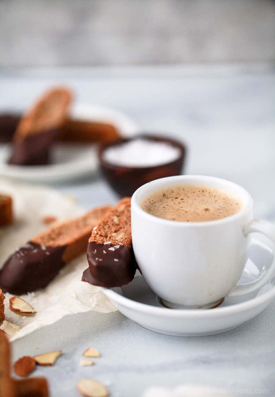 GLUTEN FREE AMARETTO BISCOTTI dipped in chocolate next to a cup of coffee