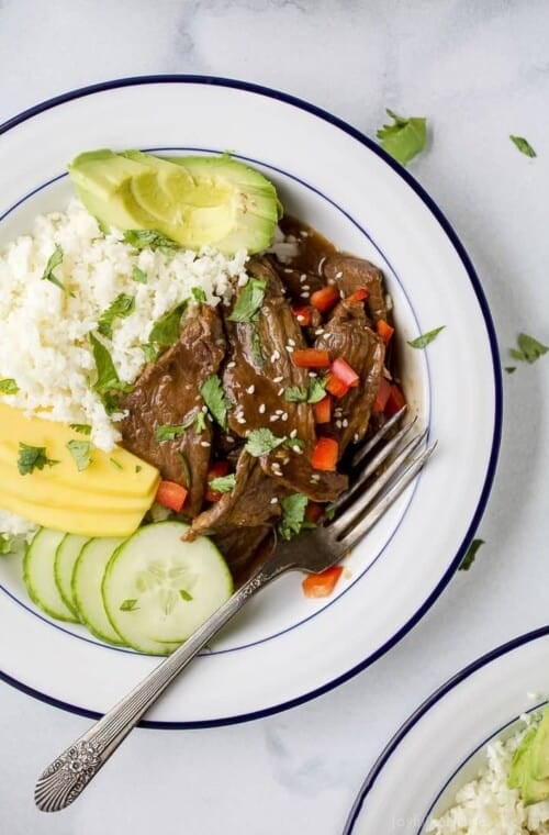 Instant Pot Korean Beef Bowls, a 30 minute meal with tender beef cooked in a sweet spicy korean sauce. This easy instant pot recipe is served on a bed of cauliflower rice with mango and avocado! Guaranteed to be a hit! #glutenfree