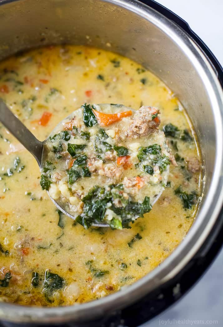This copycat zuppa toscana recipe is loaded with sausage, bacon, and fresh veggies for a comforting Instant Pot dinner. Close-up of creamy zuppa toscana in a large soup spoon straight out of the Instant Pot.