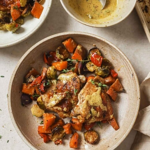 Overhead photo of a bowl with sheet pan chicken thighs and roasted veggies.