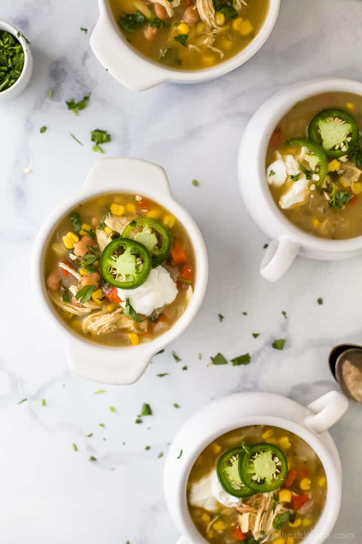 Top view of crocks of white chicken chili with jalapeno slices and sour cream.