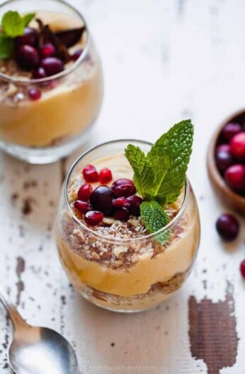 A pumpkin pie parfait on a chipped white table beside a metal spoon