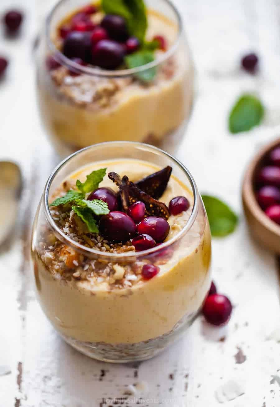 Two pumpkin parfaits in drinking glasses on a white picnic table