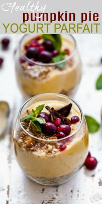 Two healthy pumpkin pie yogurt parfaits topped with pomegranate arils and cranberries