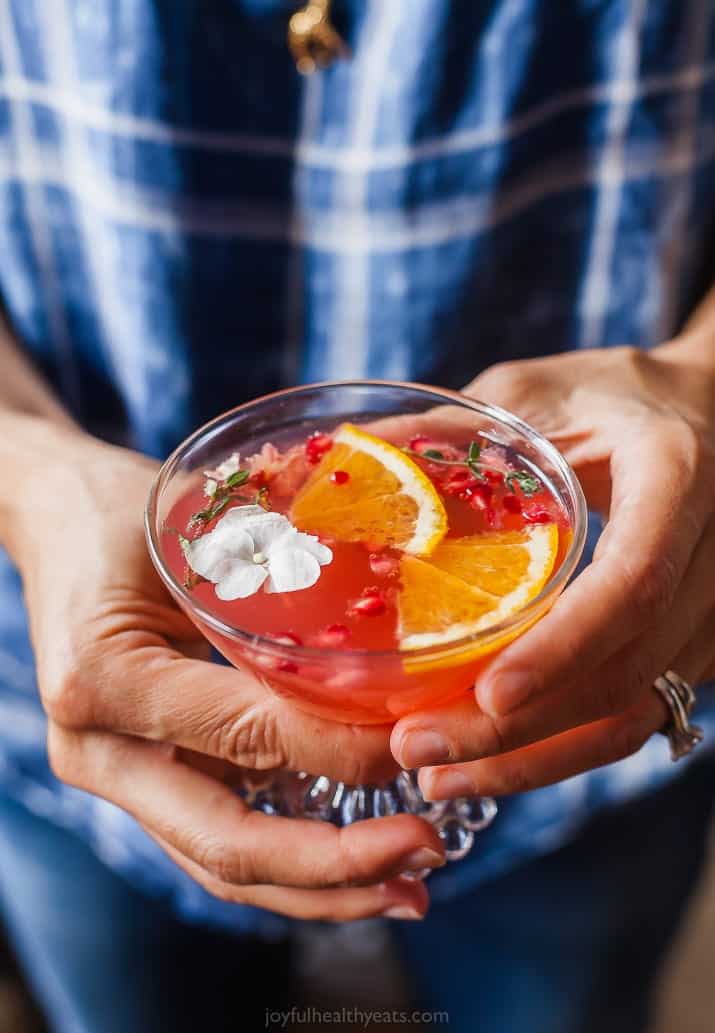 someone holding a glass of holiday pomegranate gin cocktail