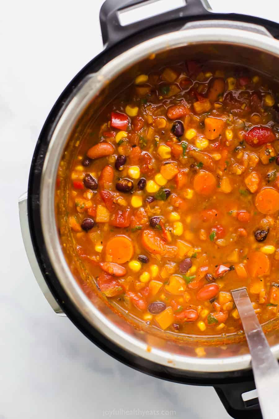 This sweet potato black bean chili is an easy Instant Pot vegetarian chili recipe made with corn, carrots, two kinds of beans, and more! Close up of instant pot sweet potato black bean chili.