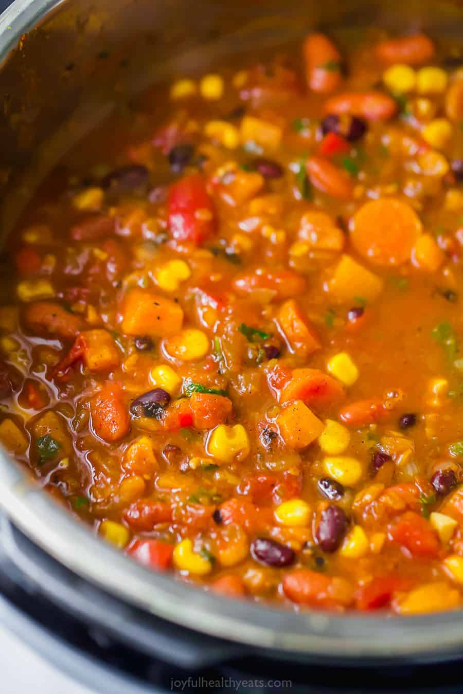 This sweet potato black bean chili is an easy Instant Pot vegetarian chili recipe made with corn, carrots, two kinds of beans, and more! Close up of sweet potato black bean chili in the instant pot.