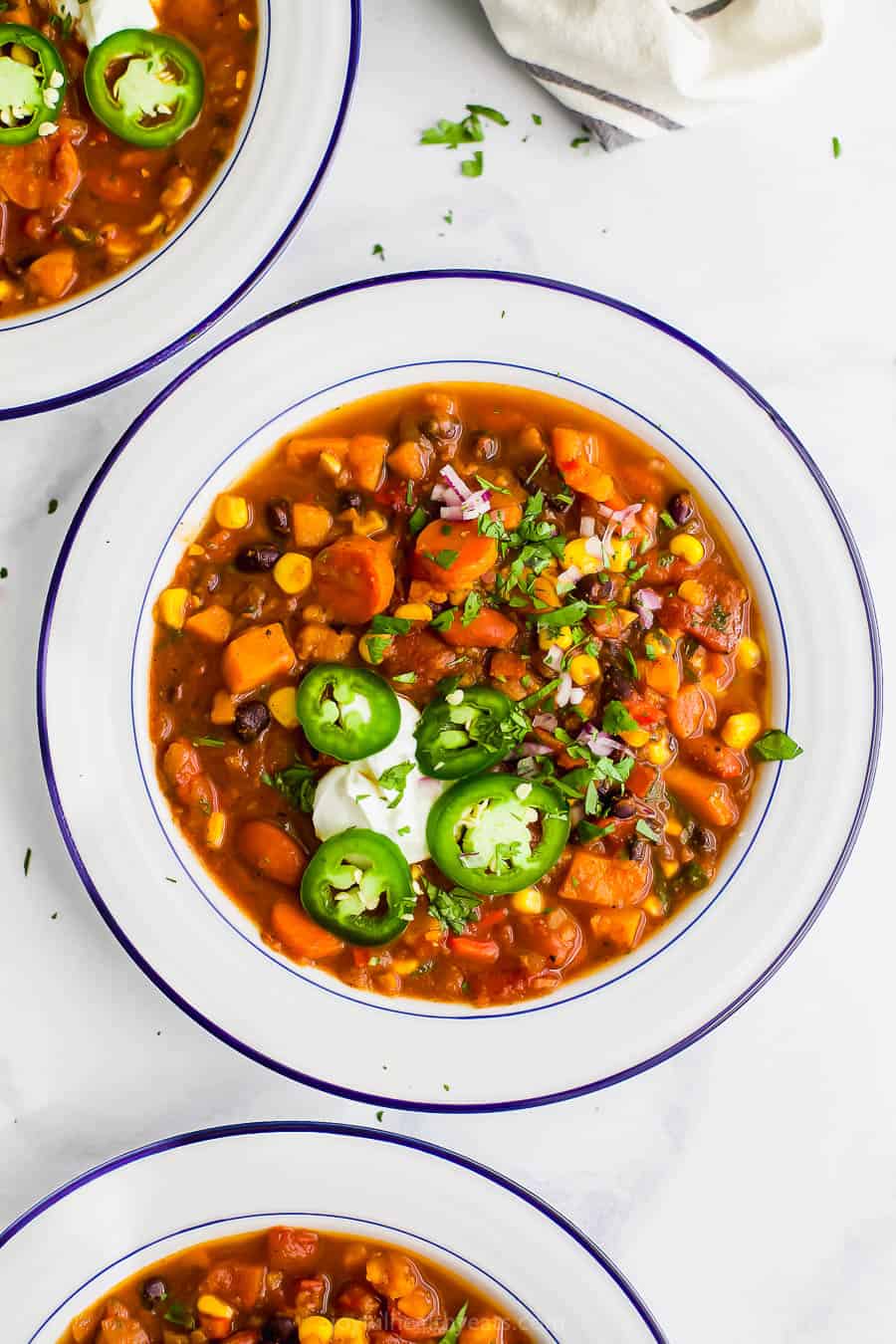 This sweet potato black bean chili is an easy Instant Pot vegetarian chili recipe made with corn, carrots, two kinds of beans, and more! Two bowls of instant pot sweet potato black bean chili.