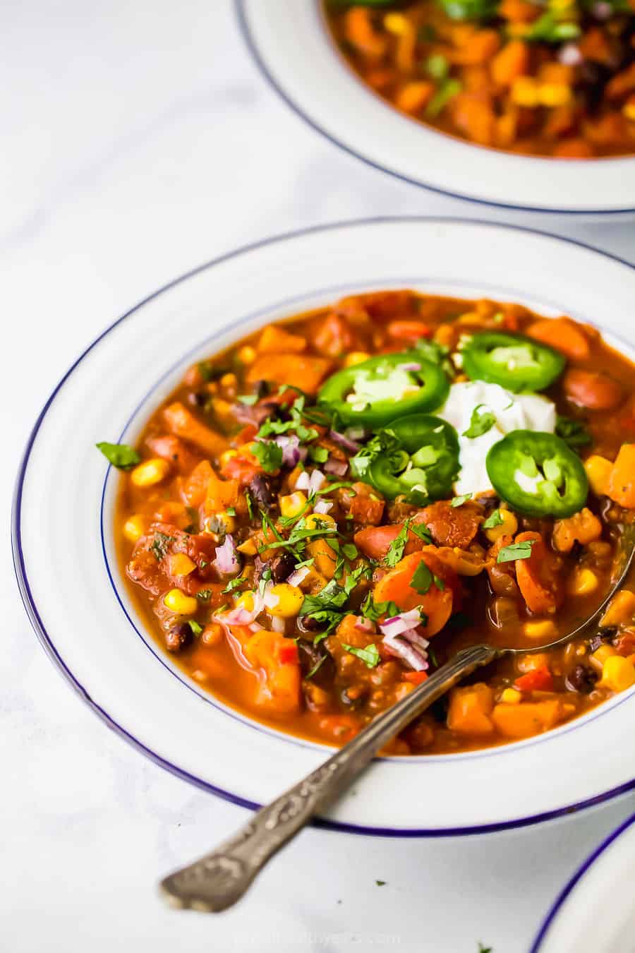 Bowl of sweet potato black bean chili with sour cream and jalapenos. 