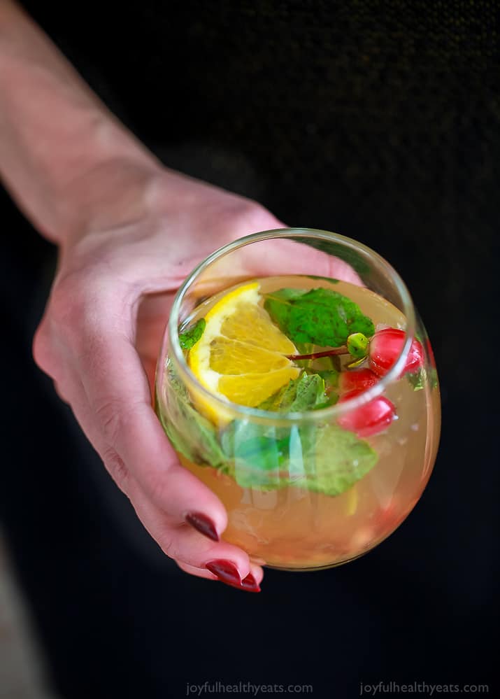 photo of a hand holding a glass of lime mint kombucha cocktail