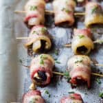 side photo of bacon wrapped figs with herb goat cheese on a baking sheet