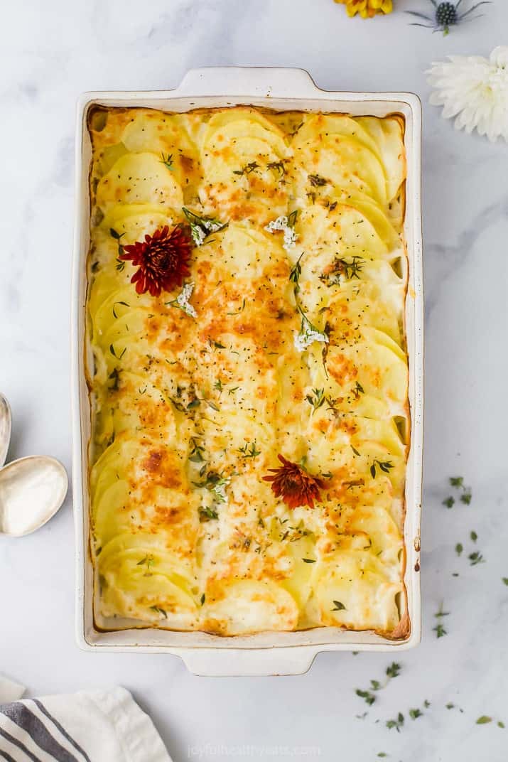 An overhead shot of a baking dish on a countertop containing cheesy scalloped potatoes