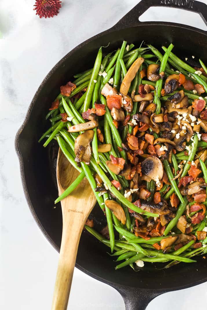 Green Bean Casserole is made with sautéed green beans, savory mushrooms and crispy bacon topped with homemade fried shallots. Green bean casserole in a skillet before adding the fried shallots.