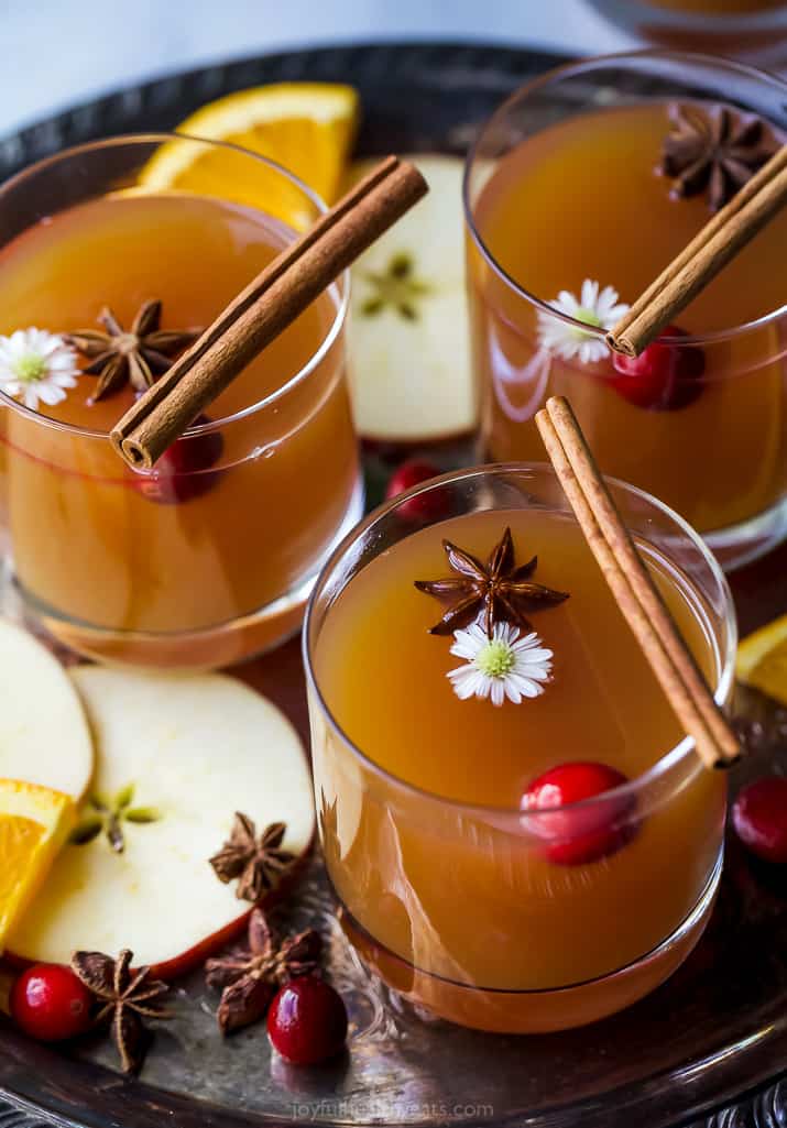 side view of hot spiked mulled apple cider in cups with cinnamon sticks
