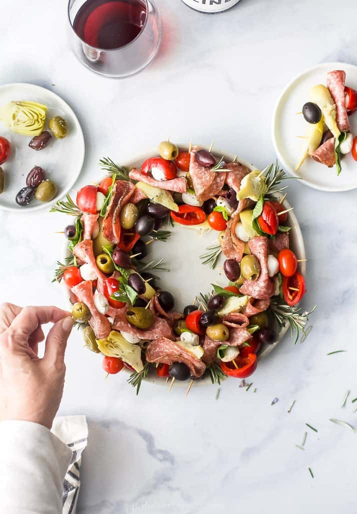 overhead photo of a hand grabbed something from a christmas wreath antipasto skewer