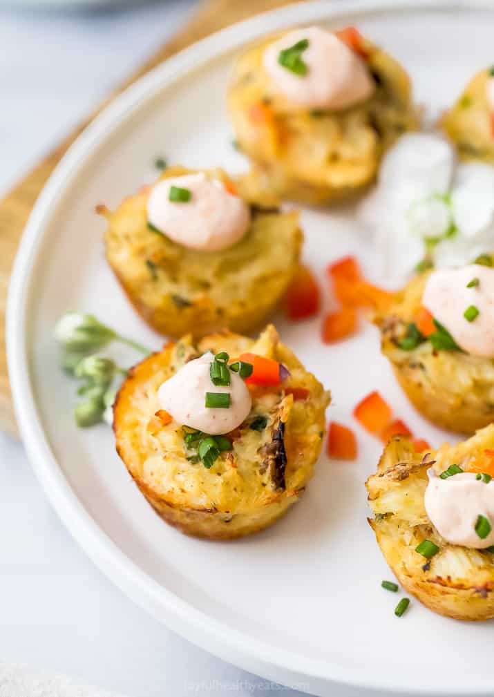 closeup photo of mini baked crab cakes with sriracha sauce on a plate