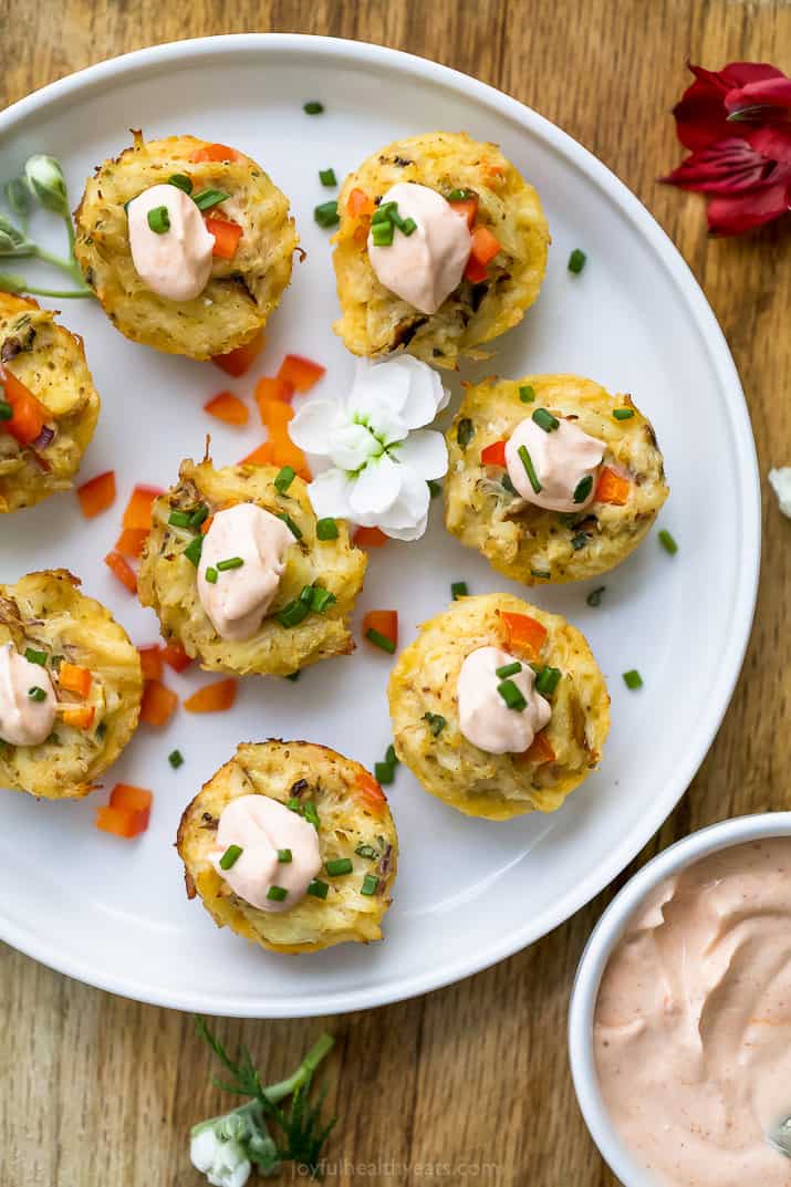 overhead photo of mini baked crab cakes with sriracha sauce on a plate