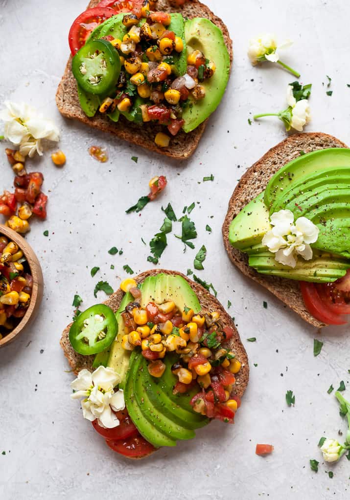 healthy avocado toast topped with charred corn salsa on a board