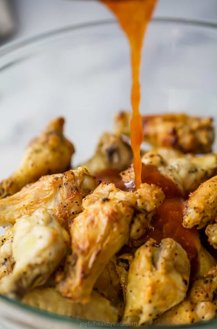 homeamde chili lime sauce being poured over baked chicken wings