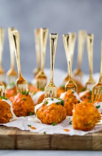 crock pot buffalo chicken meatballs drizzled with ranch dressing on a serving board