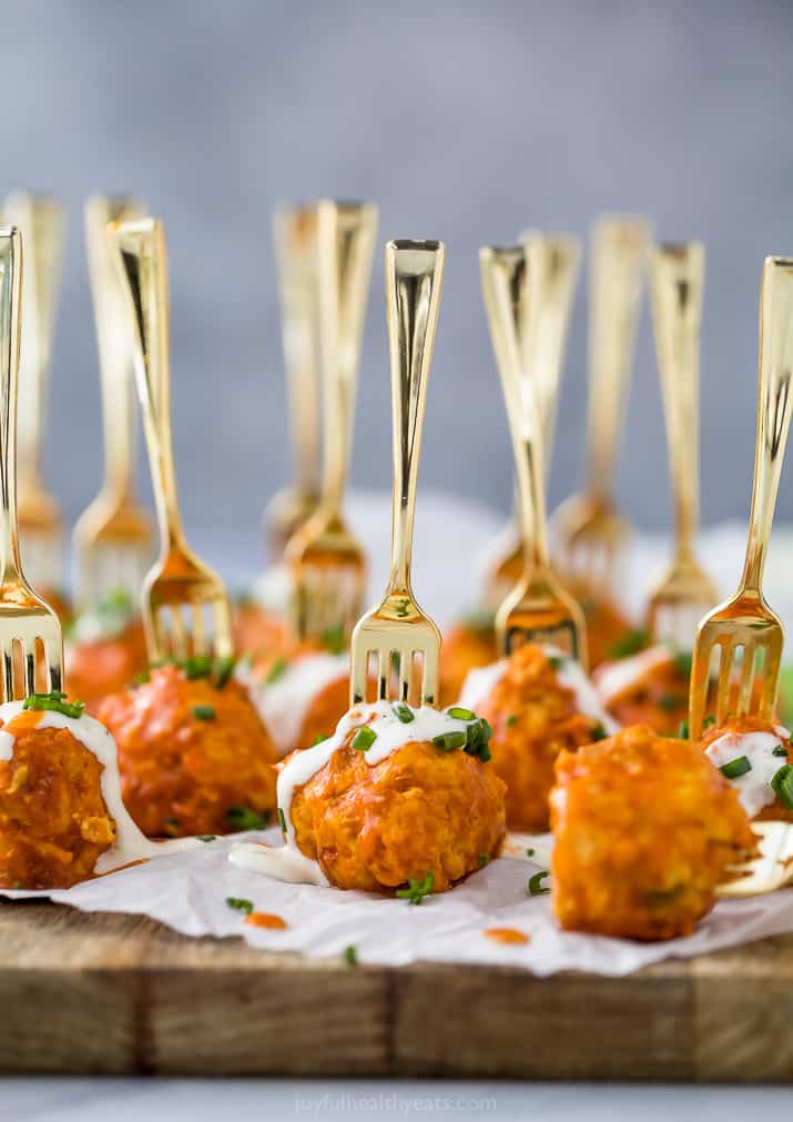 crock pot buffalo chicken meatballs drizzled with ranch dressing on a serving board