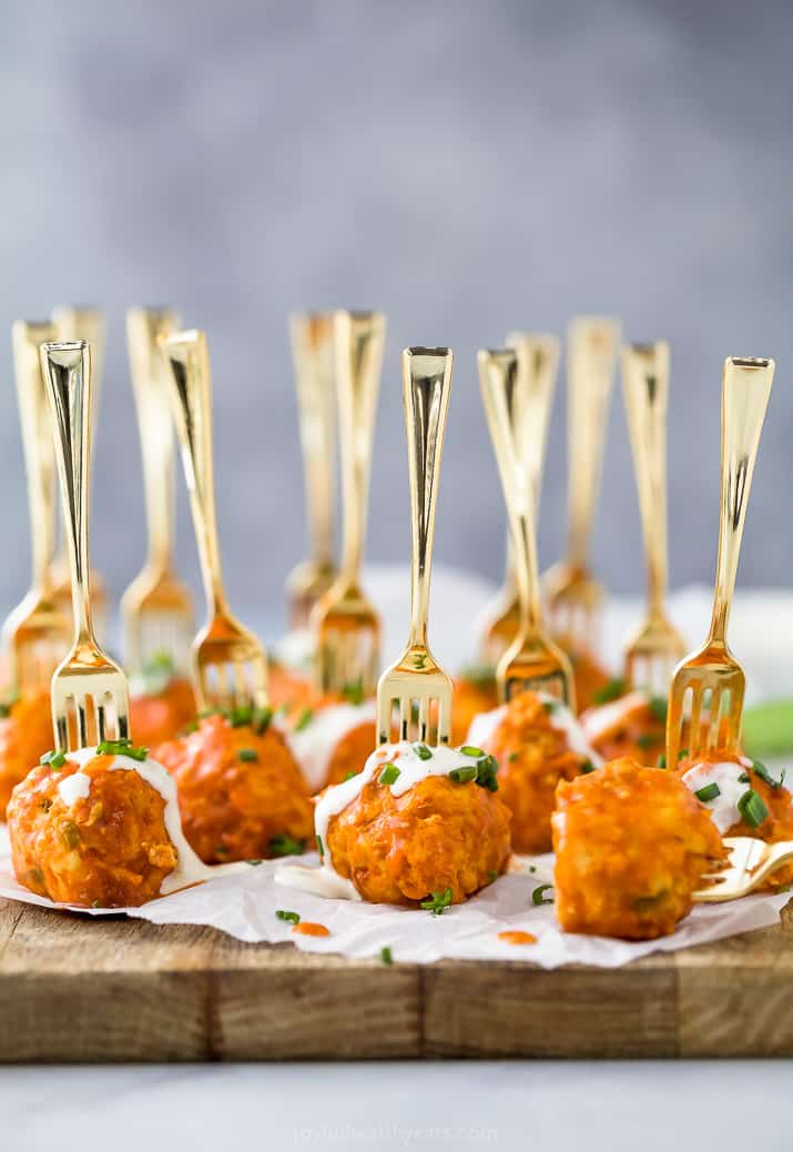 crock pot buffalo chicken meatballs drizzled with ranch dressing on a small fork