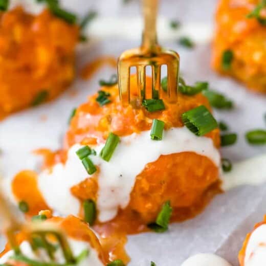 close up photo of one crock pot buffalo chicken meatball covered in ranch dressing