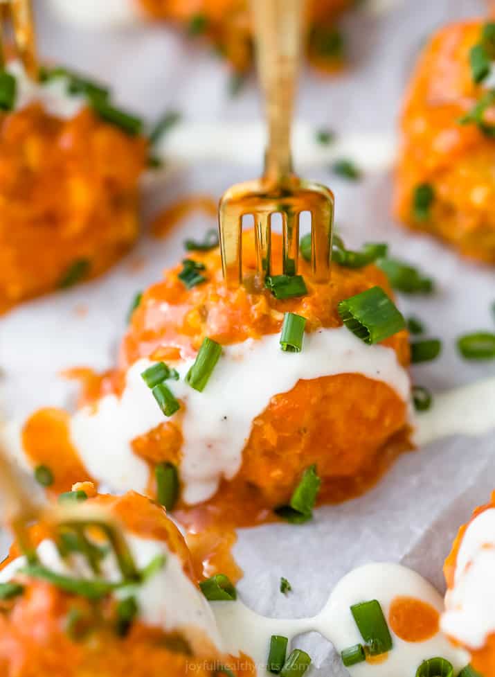 close up photo of one crock pot buffalo chicken meatball covered in ranch dressing