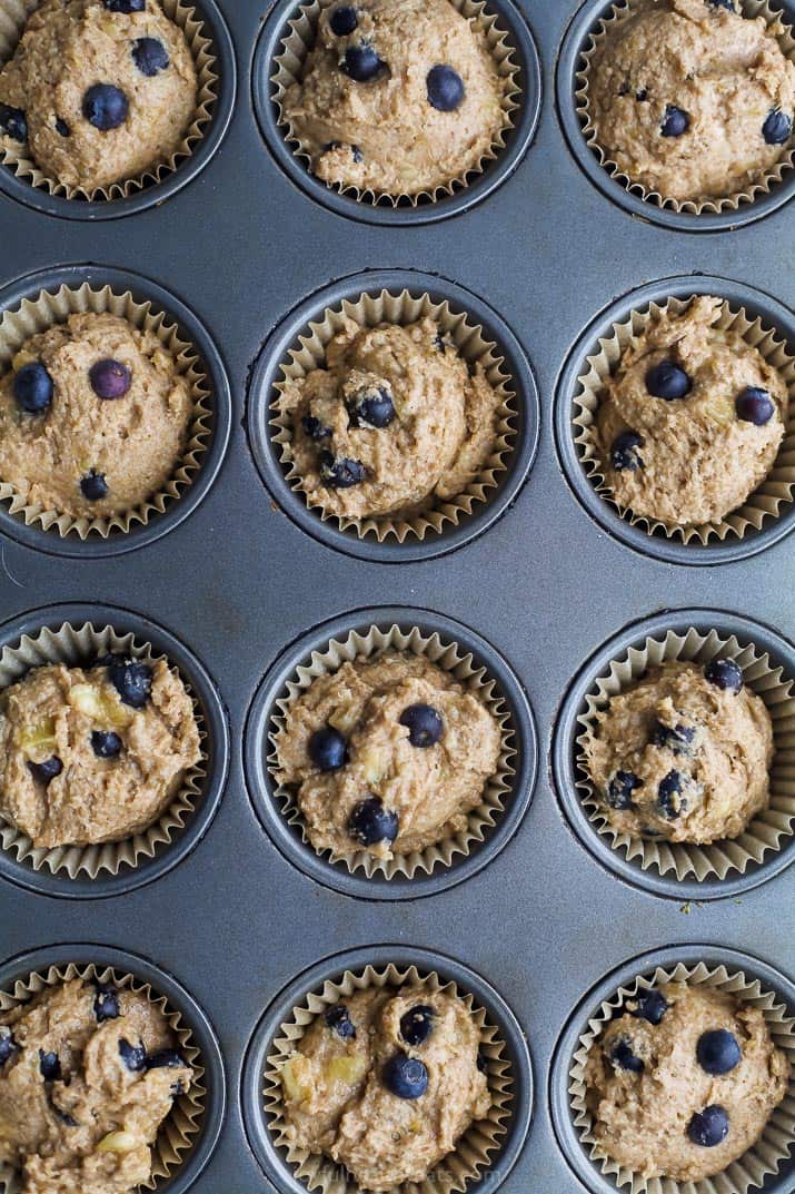 picture of healthy banana blueberry muffin batter in a muffin pan getting ready to be baked