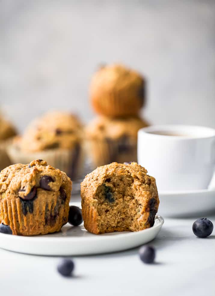 picture of healthy banana blueberry muffins on a plate, one with a bite in it