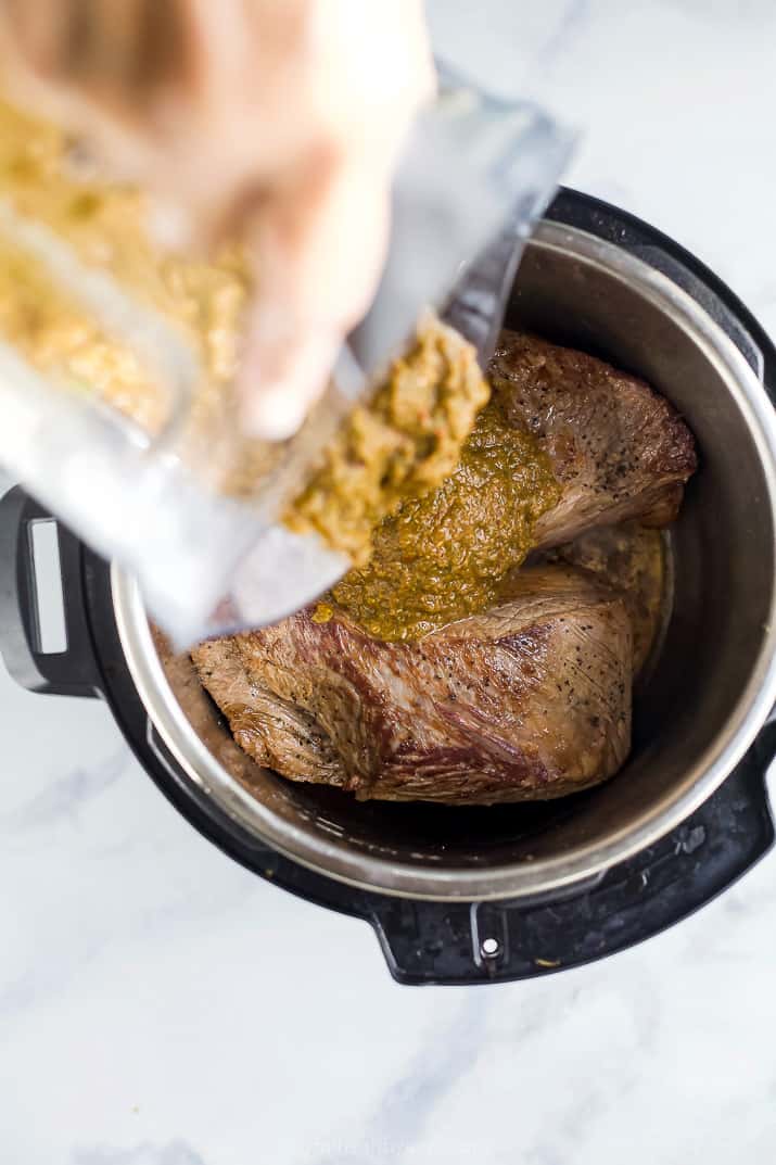 chipotle sauce being poured of beef barbacoa in an instant pot