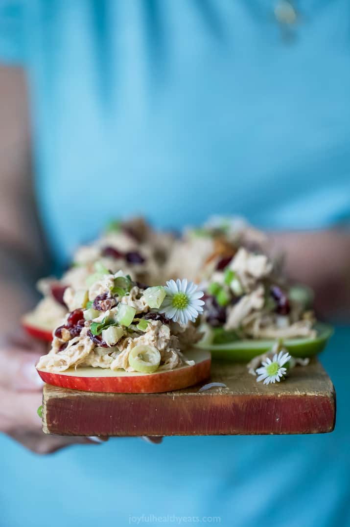Chicken salad on apple slices on a wood board