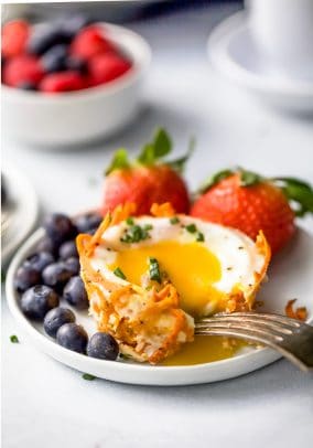 a yolk being cracked in sweet potato hash baked egg cups