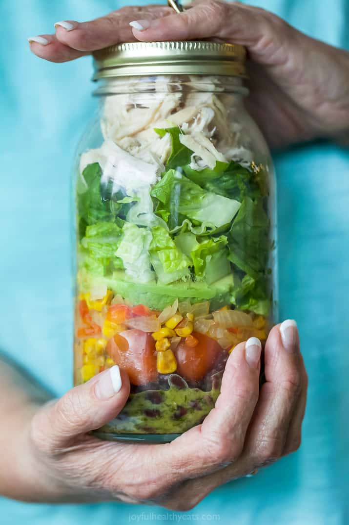 two hands holding a Mason Jar filled with Southwest Chicken Salad with Cilantro Lime Dressing