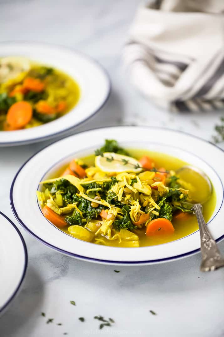 side view of healing chicken soup recipe served in bowl a topped with lemon