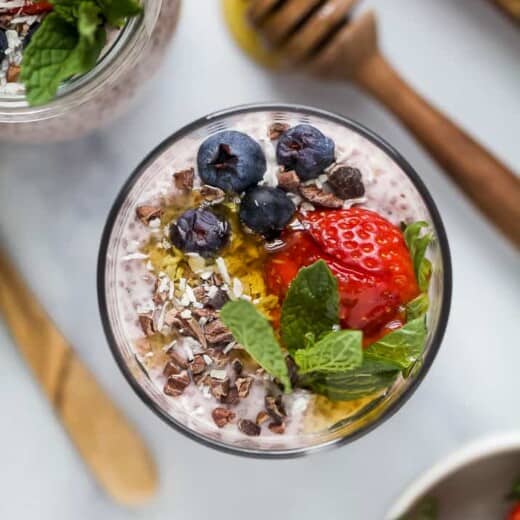 overhead photo of strawberry chia pudding in a glass jar topped with fresh fruit