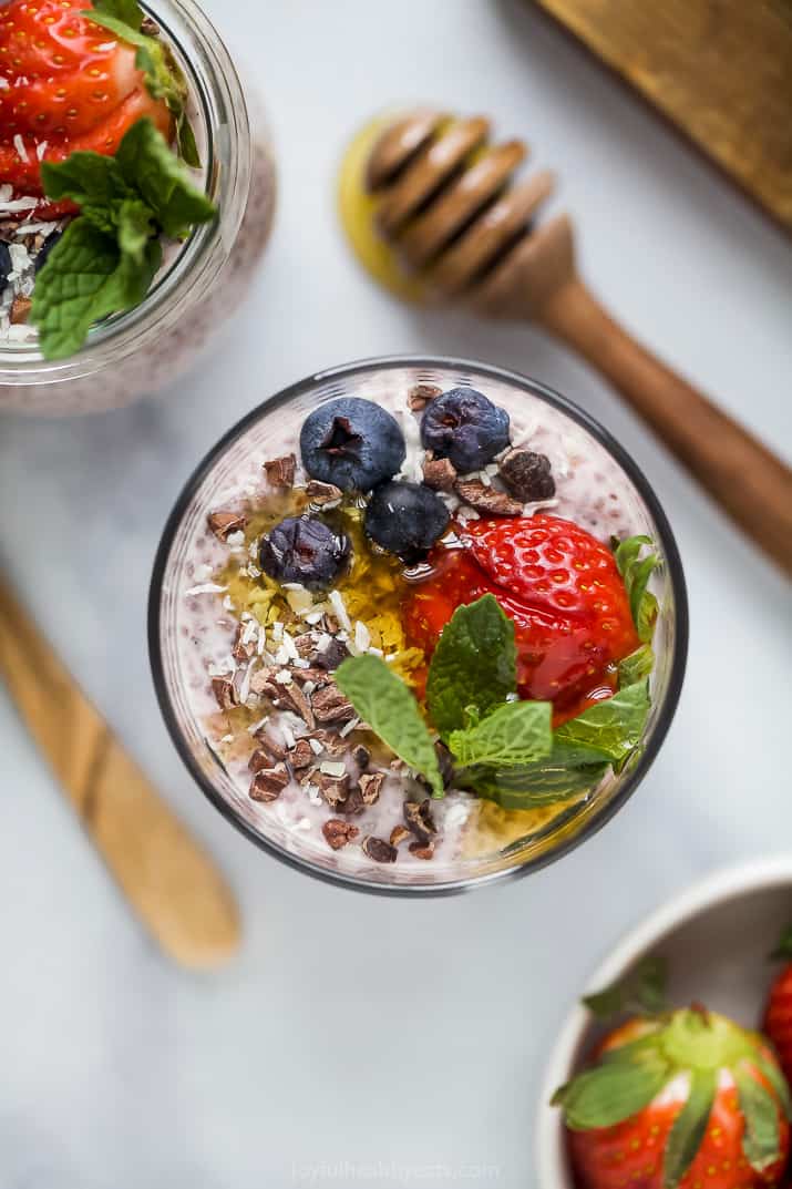 overhead photo of strawberry chia pudding in a glass jar topped with fresh fruit