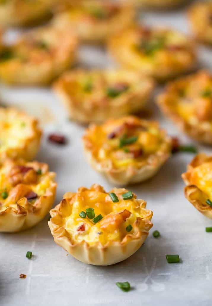 ham and cheese mini quiches topped with chives on parchment paper