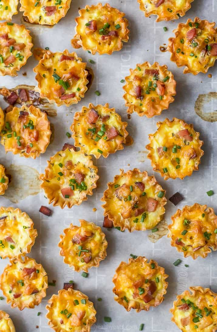ham and cheese mini quiches topped with chives on parchment paper