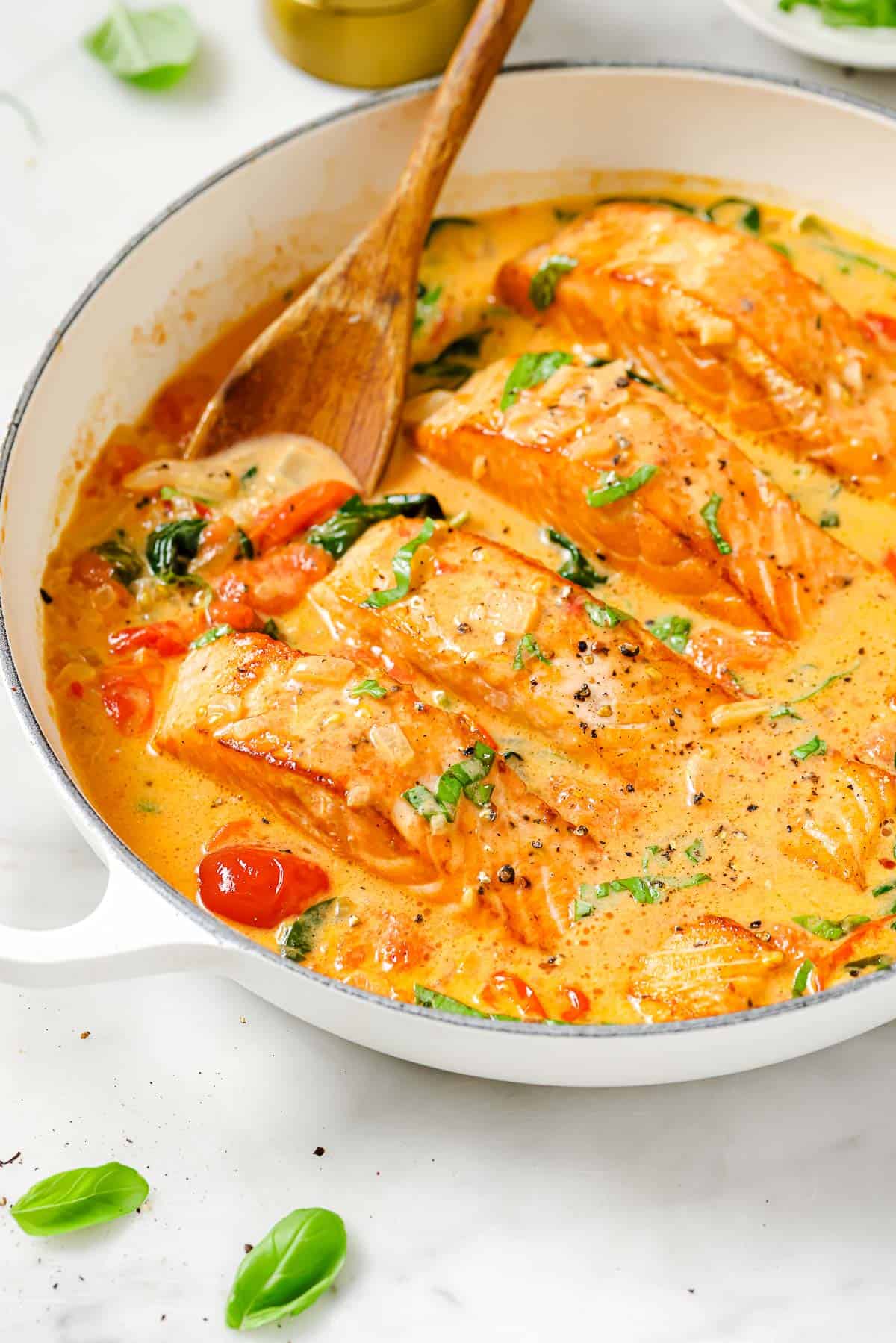 Creamy tuscan salmon in the pan with cherry tomatoes and spinach. 