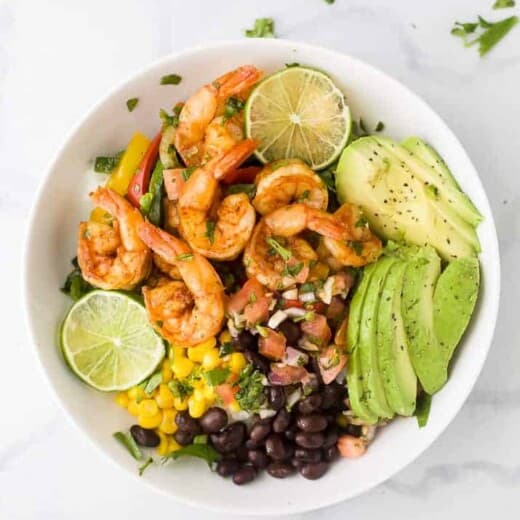 sheet pan shrimp shrimp in a bowl with avocado and pice de gallo