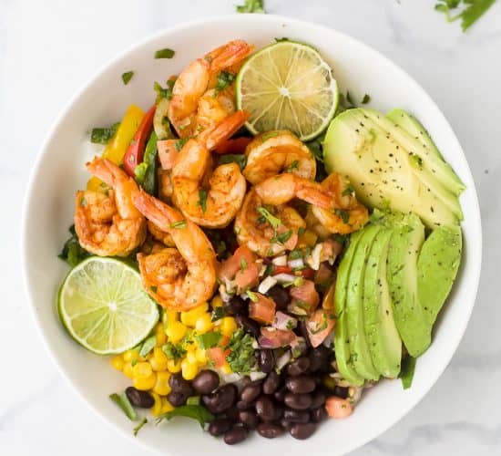 sheet pan shrimp shrimp in a bowl with avocado and pice de gallo