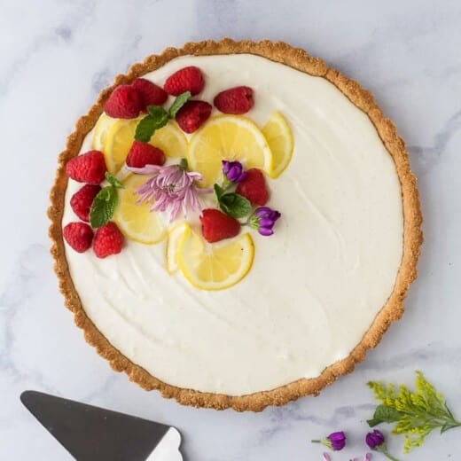 Creamy Lemon Tart Recipe with Almond Crust with flowers and berry on top