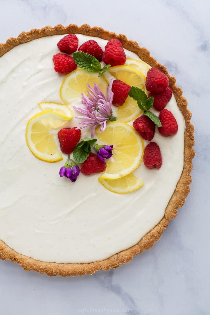 Creamy Lemon Tart Recipe with Almond Crust with flowers and fruit on top